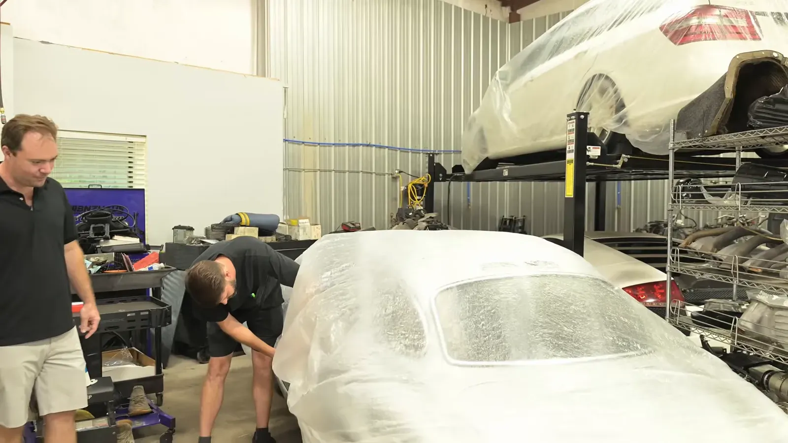 A 1955 Mercedes-Benz 300 SL under a cover on the DC MotorWerks shop floor