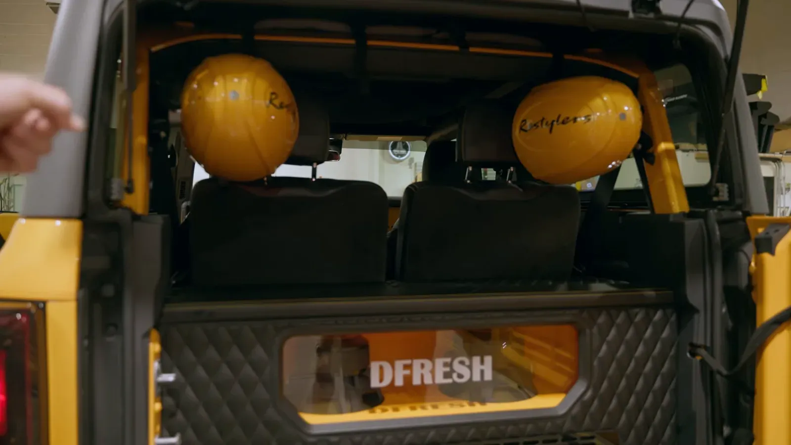 The cargo area of the yellow Bronco, a diamond-stitched subwoofer enclosure lit with the name DFRESH below the rear seats