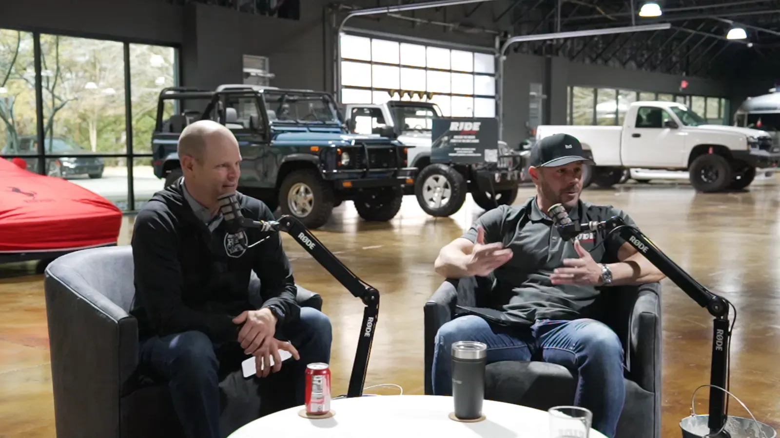 Chau Nguyen talking on the Throttlecast set at The Ride Lounge, cars on the floor behind