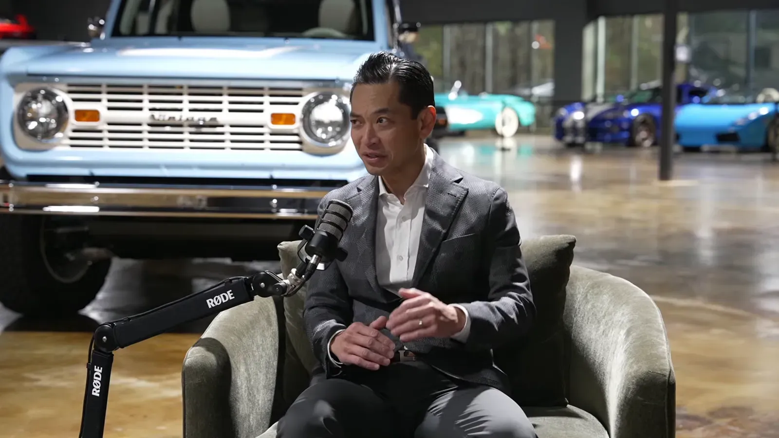 Chau Nguyen talking on the Throttlecast set at The Ride Lounge, cars on the floor behind