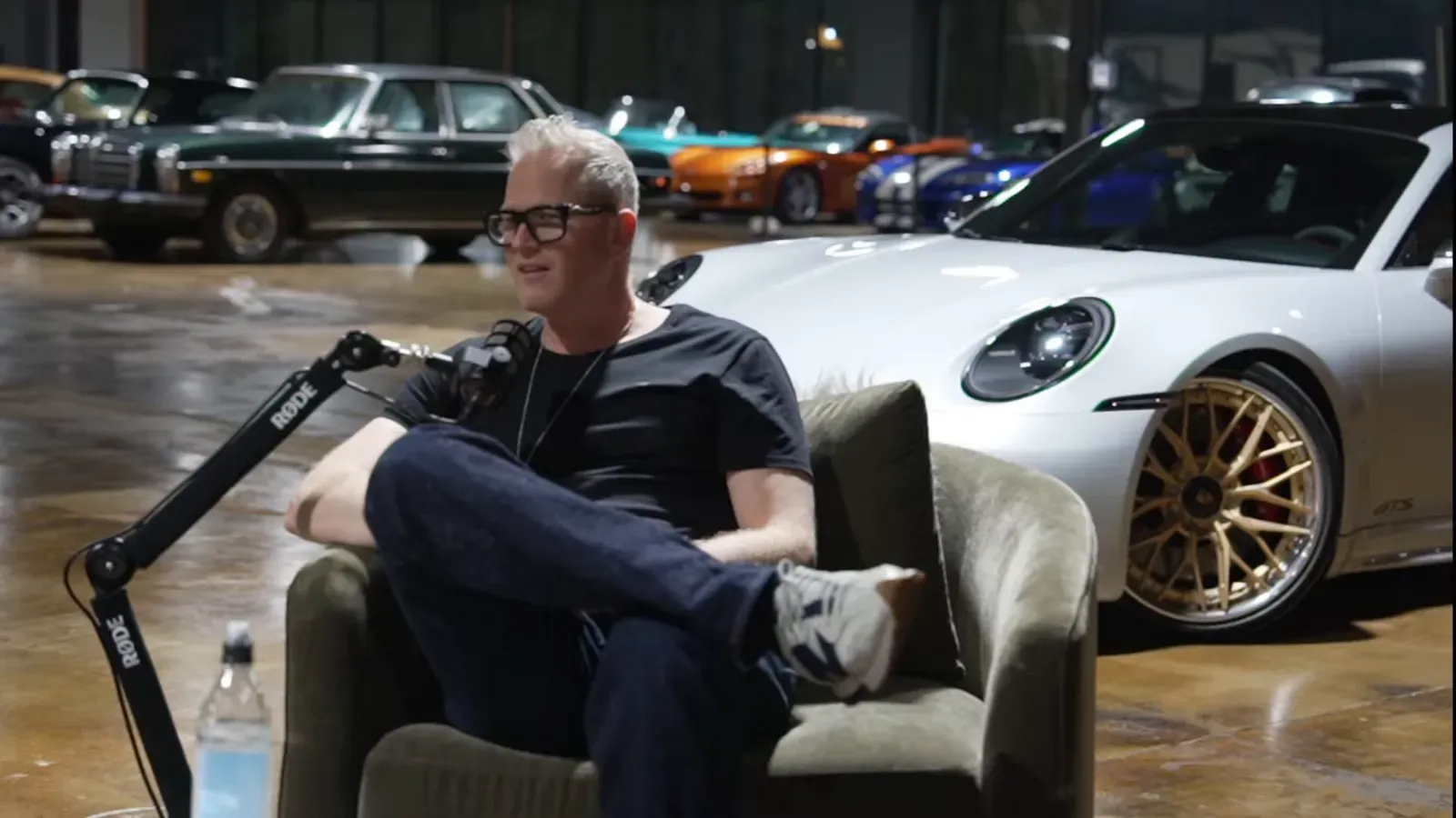 Dani Butler talking on the Throttlecast set at The Ride Lounge, cars on the floor behind