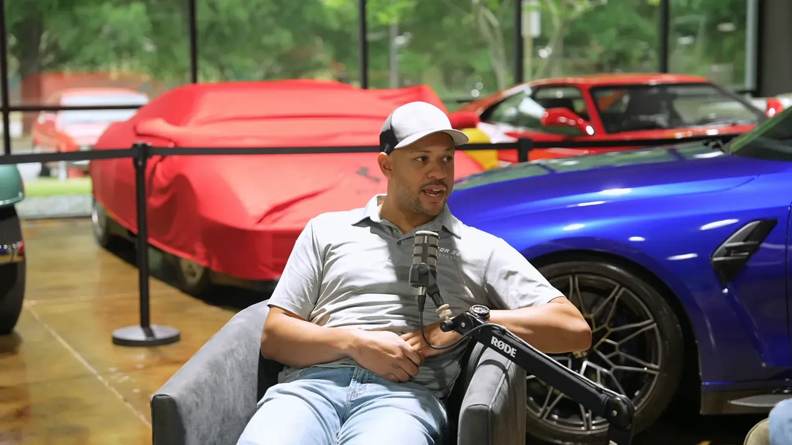 Derick Lee talking on the Throttlecast set at The Ride Lounge, cars on the floor behind