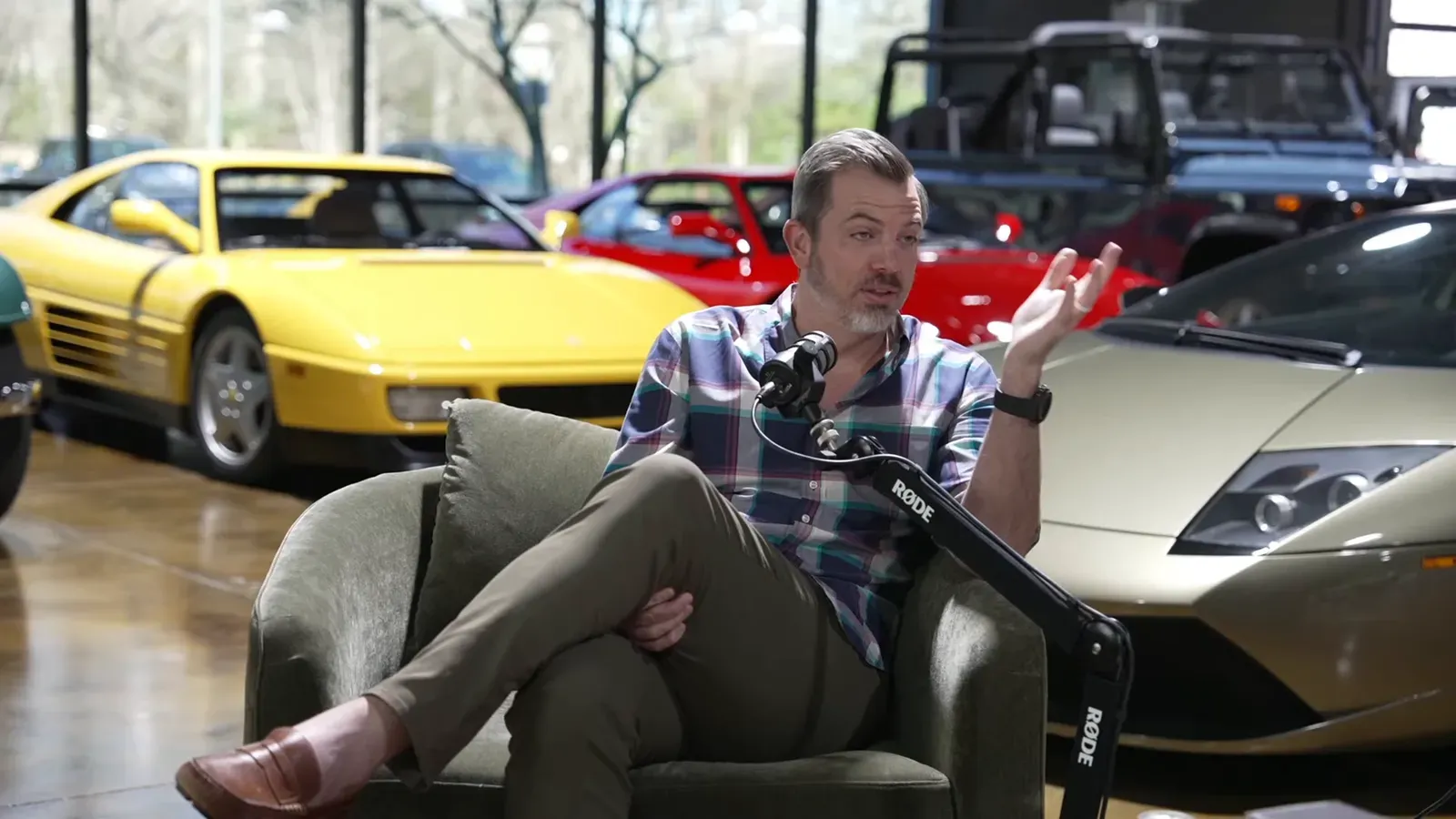 Ed Bolian talking on the Throttlecast set at The Ride Lounge, cars on the floor behind