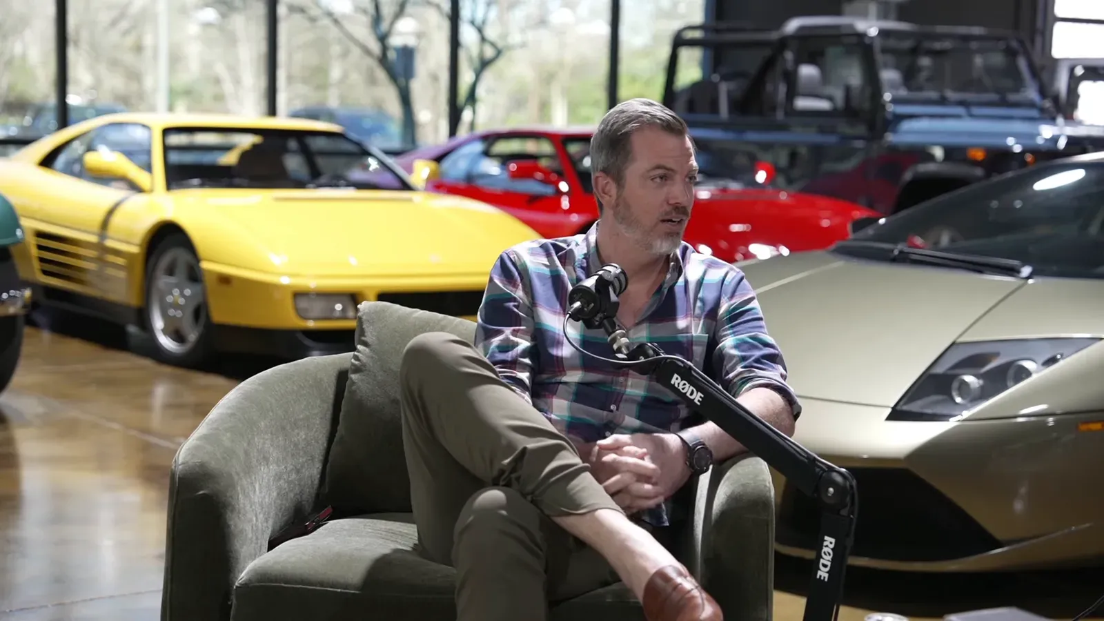 Ed Bolian talking on the Throttlecast set at The Ride Lounge, cars on the floor behind