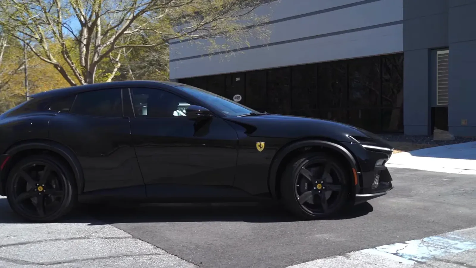 A black Ferrari Purosangue in side profile outside The Ride Lounge