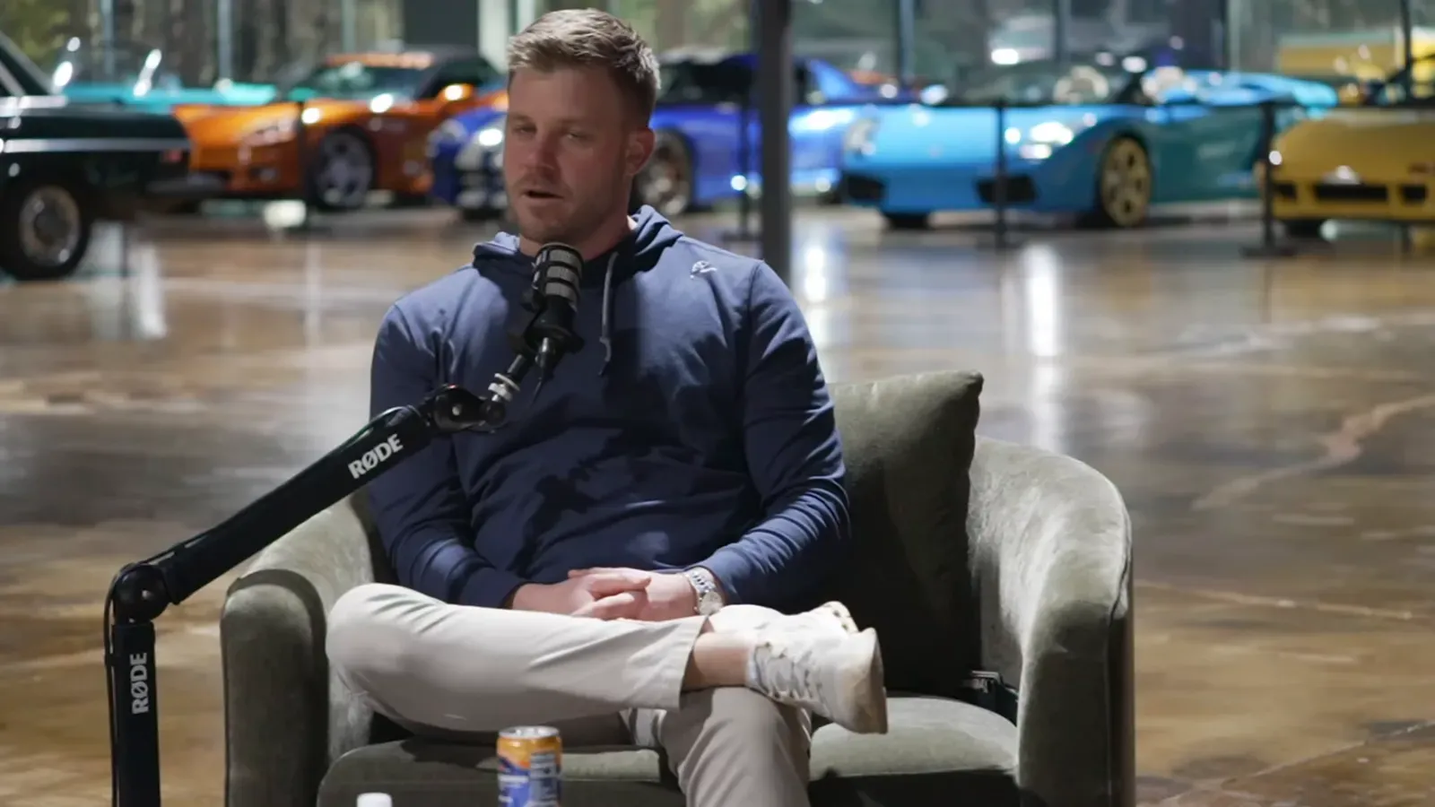 Evan Halliday talking on the Throttlecast set at The Ride Lounge, cars on the floor behind