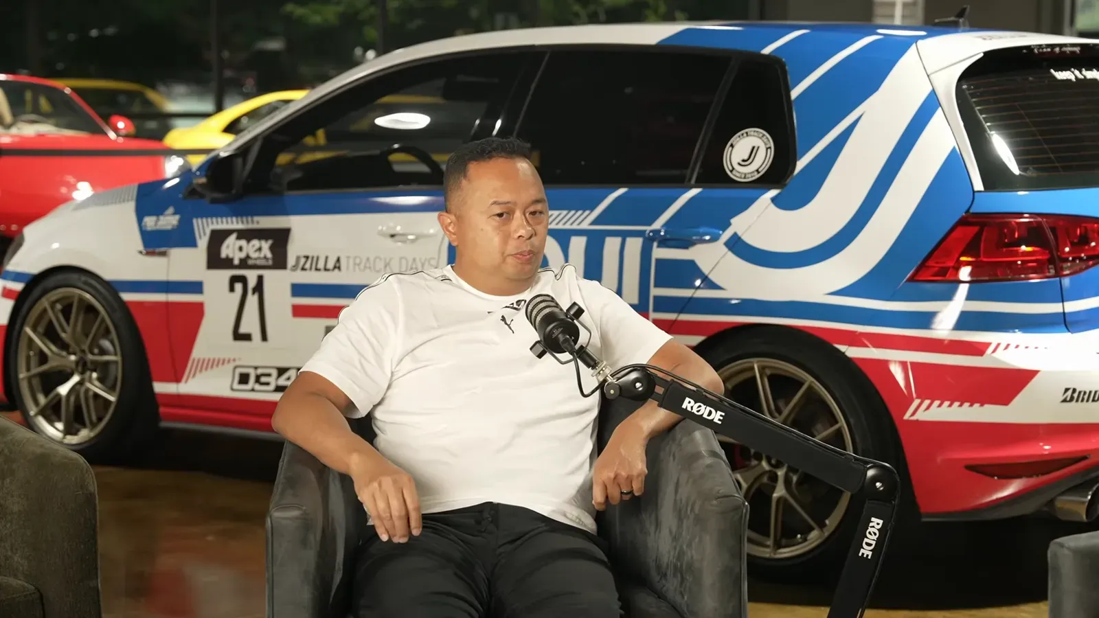James Marcellana talking on the Throttlecast set at The Ride Lounge, cars on the floor behind