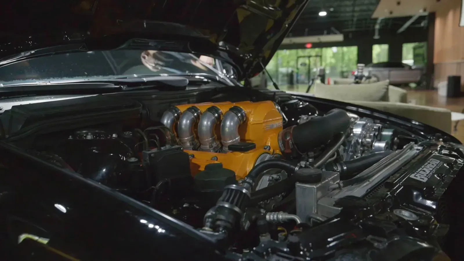The open engine bay of Jason Cummins’s black E39 M5 with an orange intake manifold