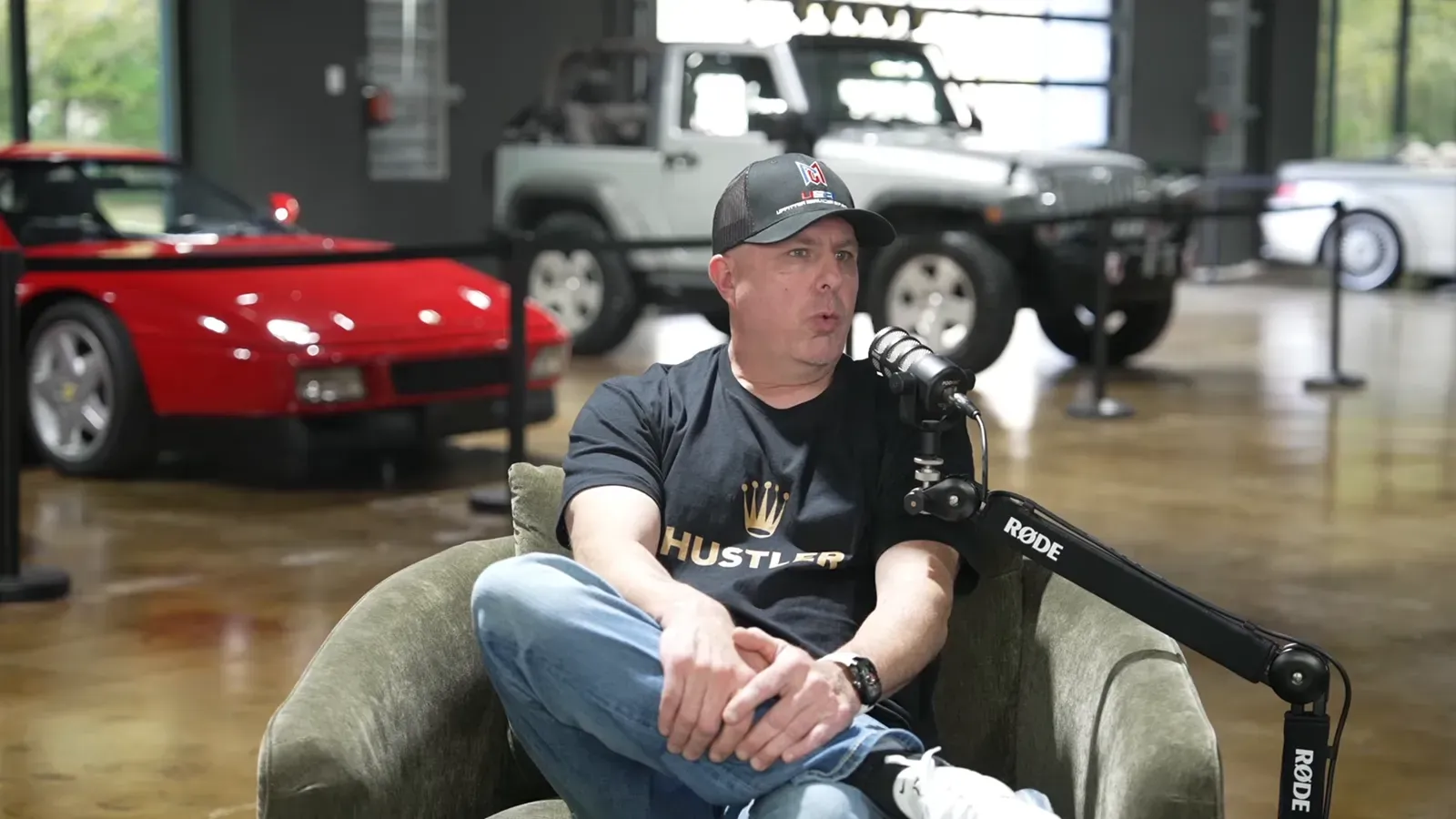 Jim Florek talking on the Throttlecast set at The Ride Lounge, cars on the floor behind