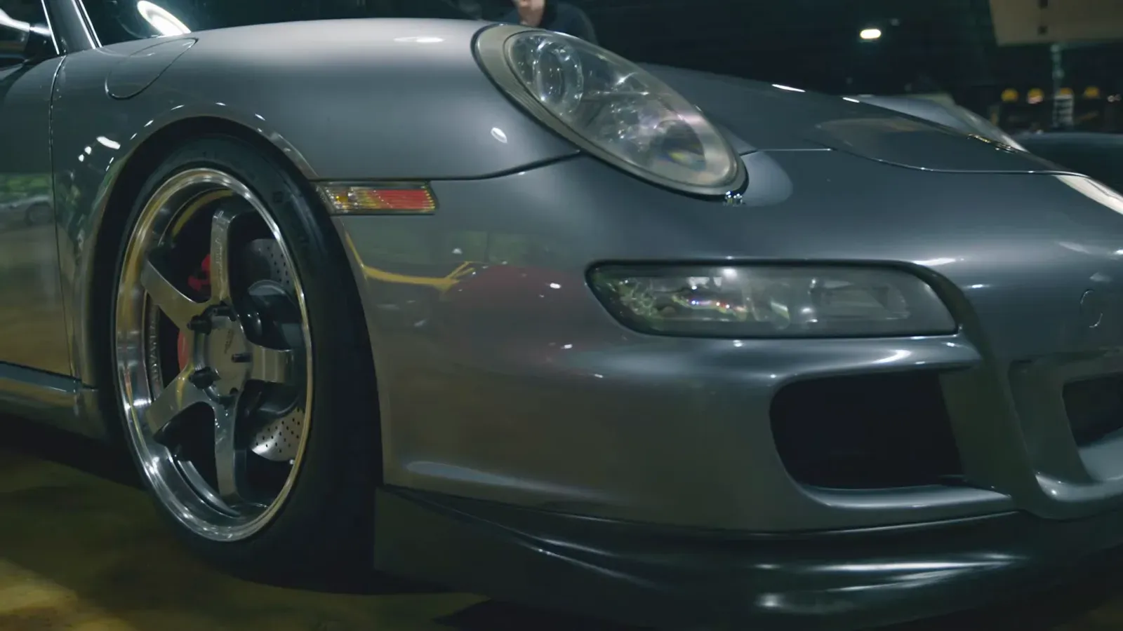 Front corner of Marat Pashkevich’s grey 2005 Porsche 997, showing the aero-kit bumper and a five-spoke wheel