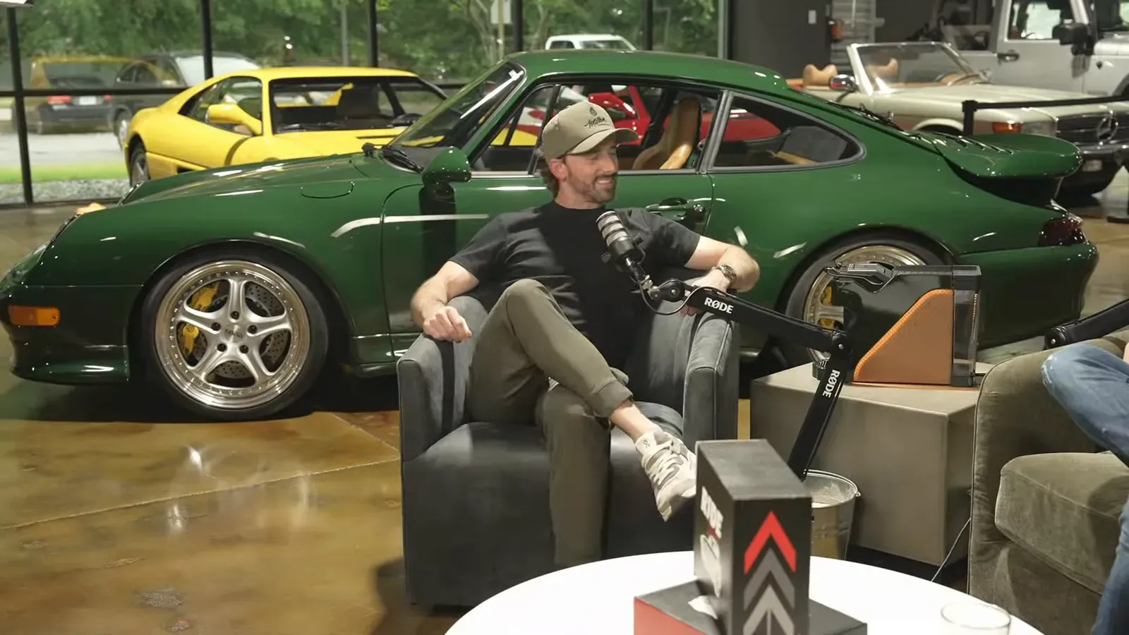 Matt Kossoff talking on the Throttlecast set at The Ride Lounge, cars on the floor behind