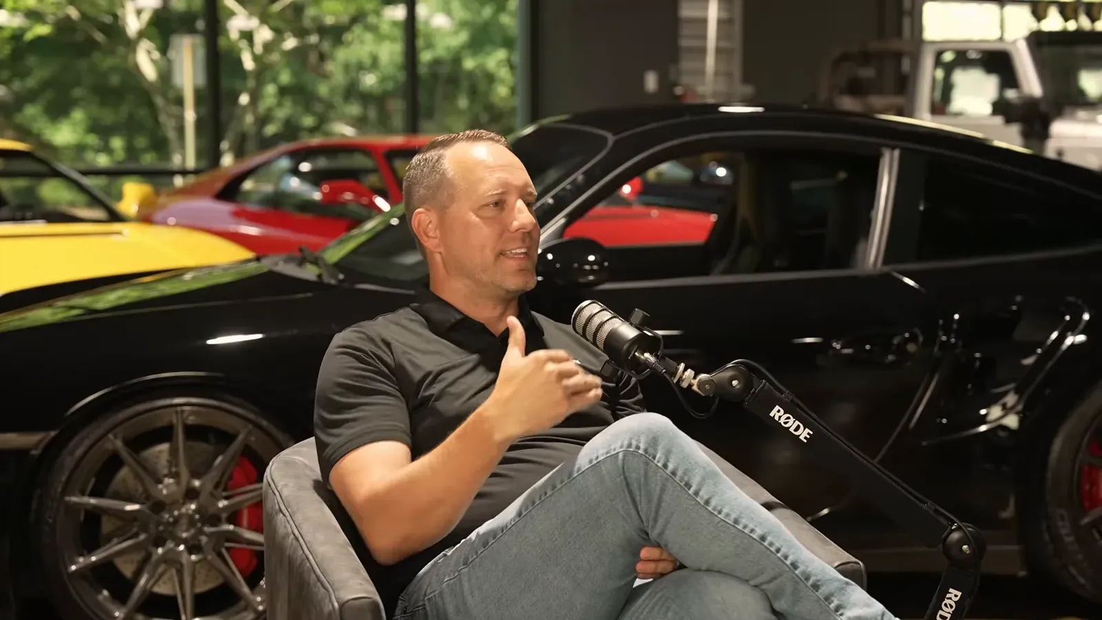 Matt Lamarsh talking on the Throttlecast set at The Ride Lounge, cars on the floor behind