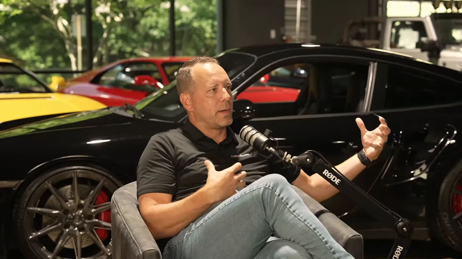 Matt Lamarsh talking on the Throttlecast set at The Ride Lounge, cars on the floor behind