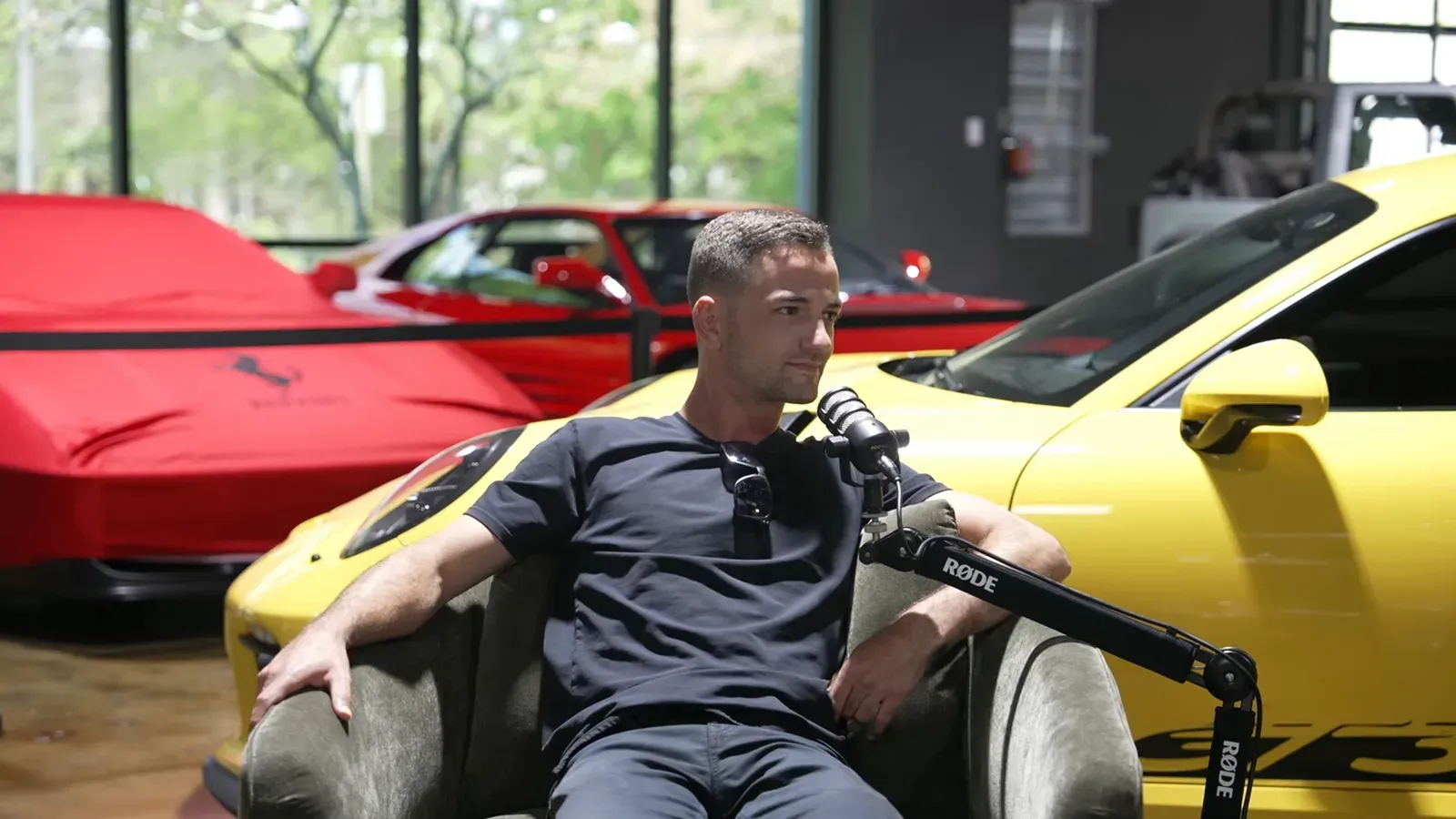 Parker Smith talking on the Throttlecast set at The Ride Lounge, cars on the floor behind