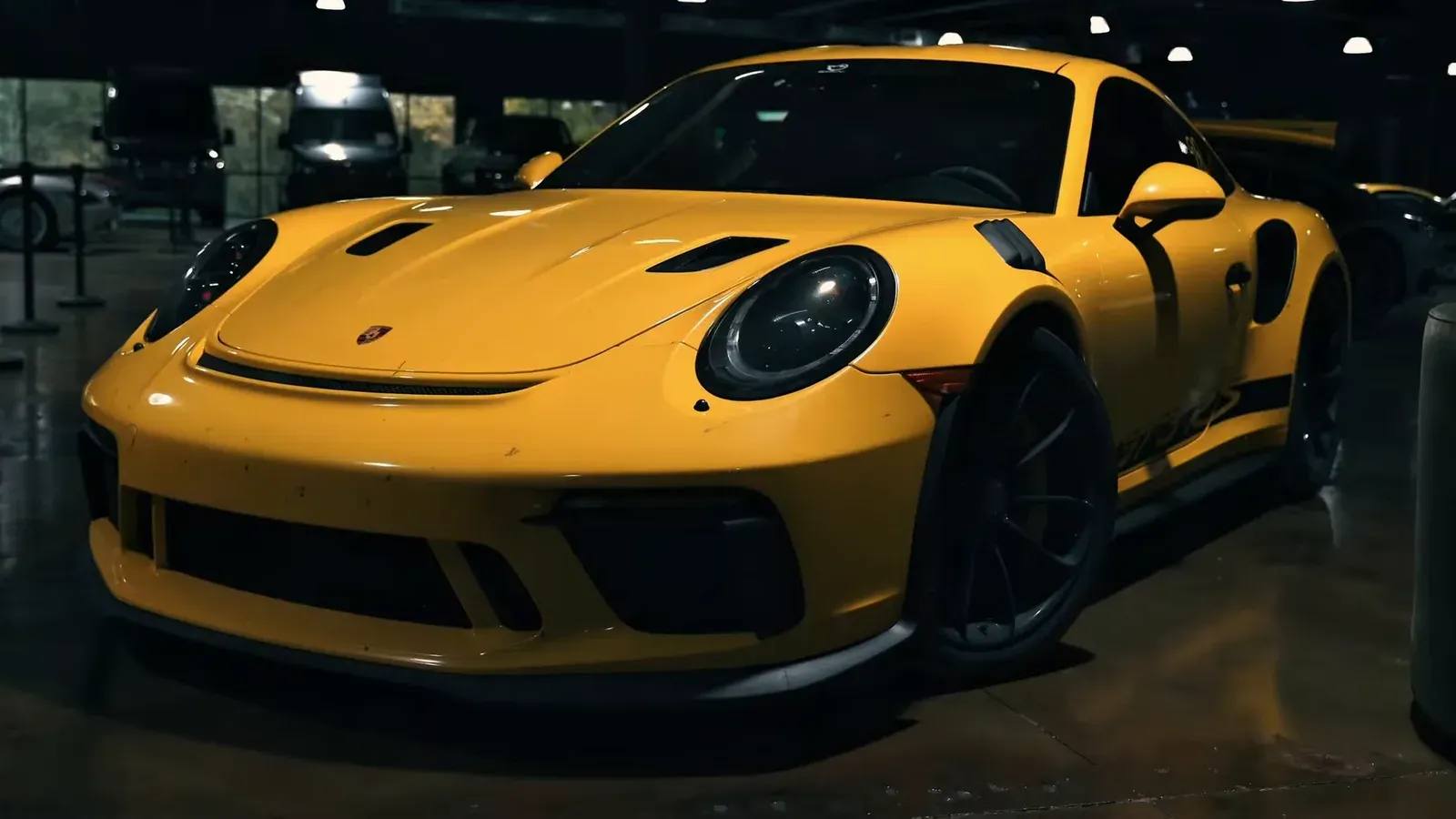 A Racing Yellow Porsche 991.2 GT3 RS parked on the lounge floor, seen from the front three-quarter
