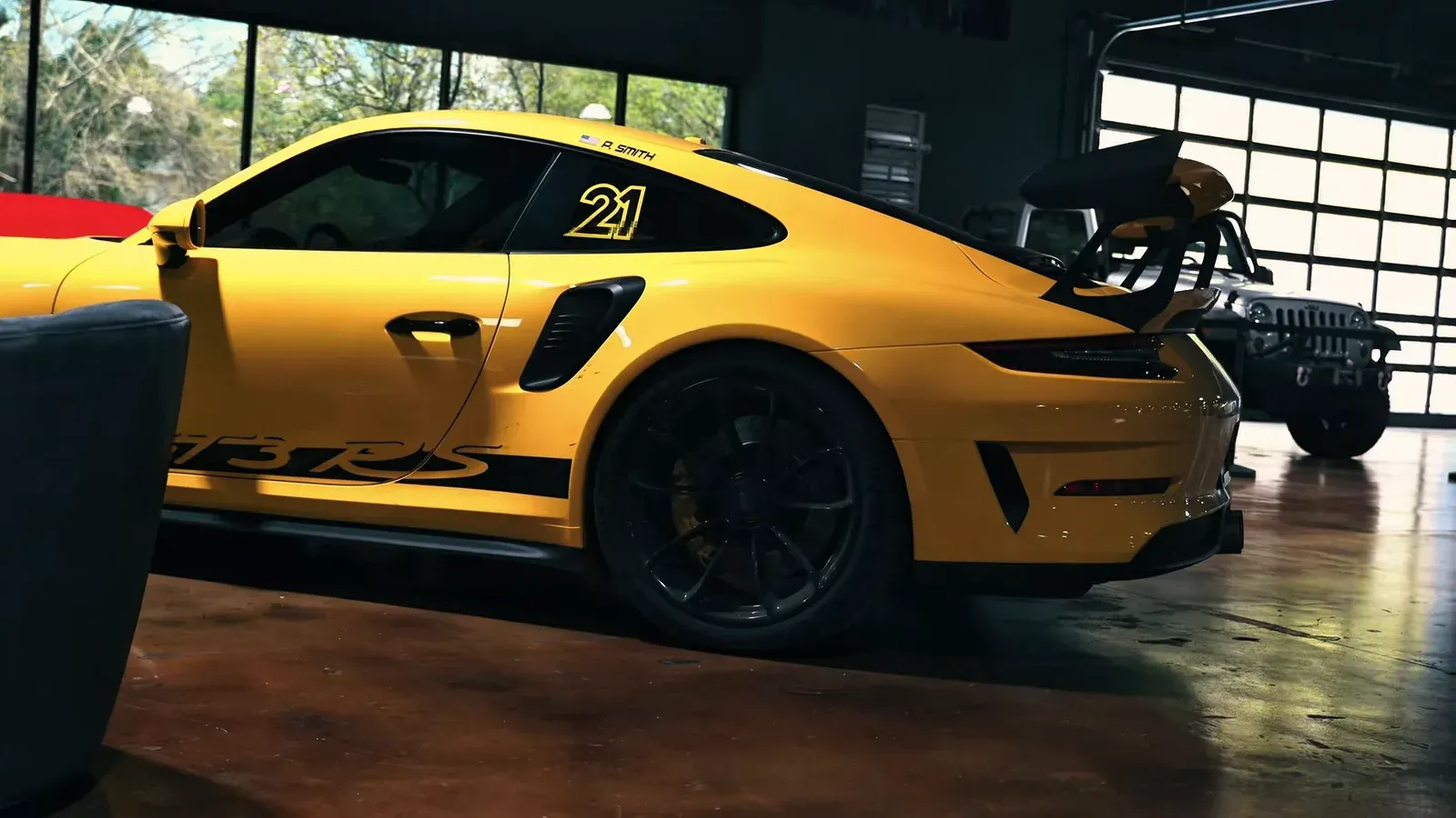 Side view of Parker Smith’s yellow Porsche GT3 RS with GT3 RS side decals and the number 21 on the rear window