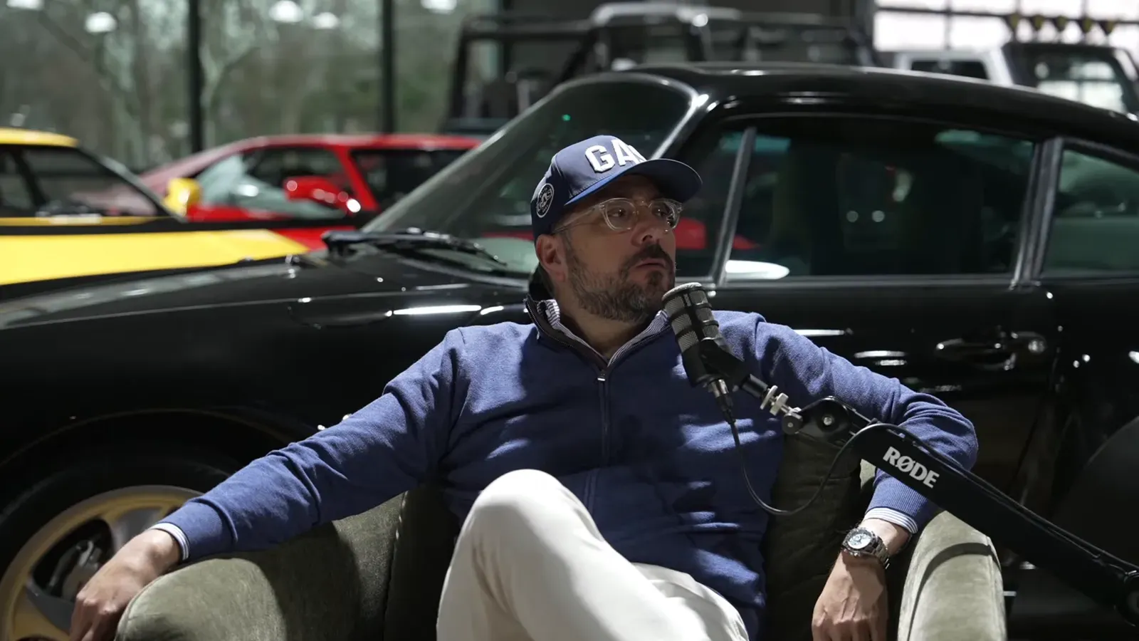 Tony Marzullo talking on the Throttlecast set at The Ride Lounge, cars on the floor behind