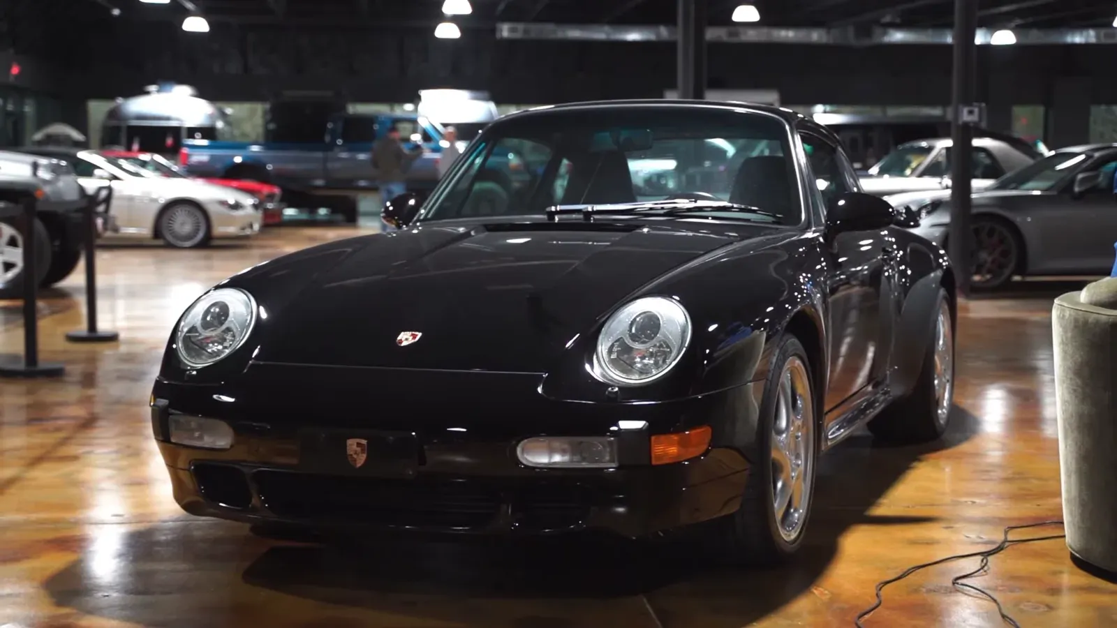 A black 1996 Porsche 993 Turbo parked on the lounge floor, seen from the front