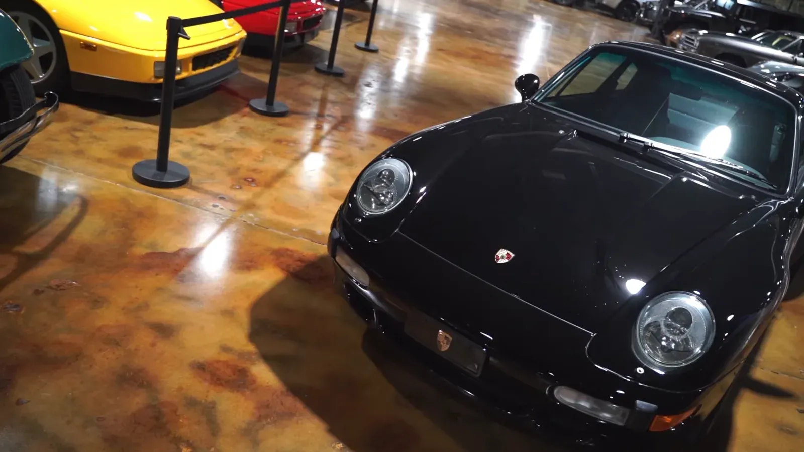 The black Porsche 993 Turbo from the front three-quarter, a yellow and a red car roped off behind it