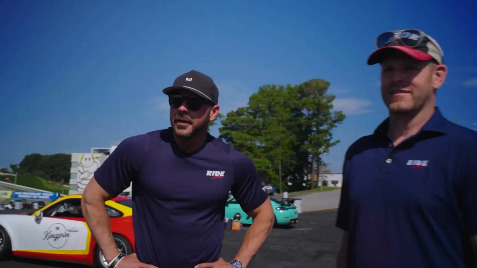 Adam Sekulow and Grant Brewer in the Privé paddock, Porsches behind them