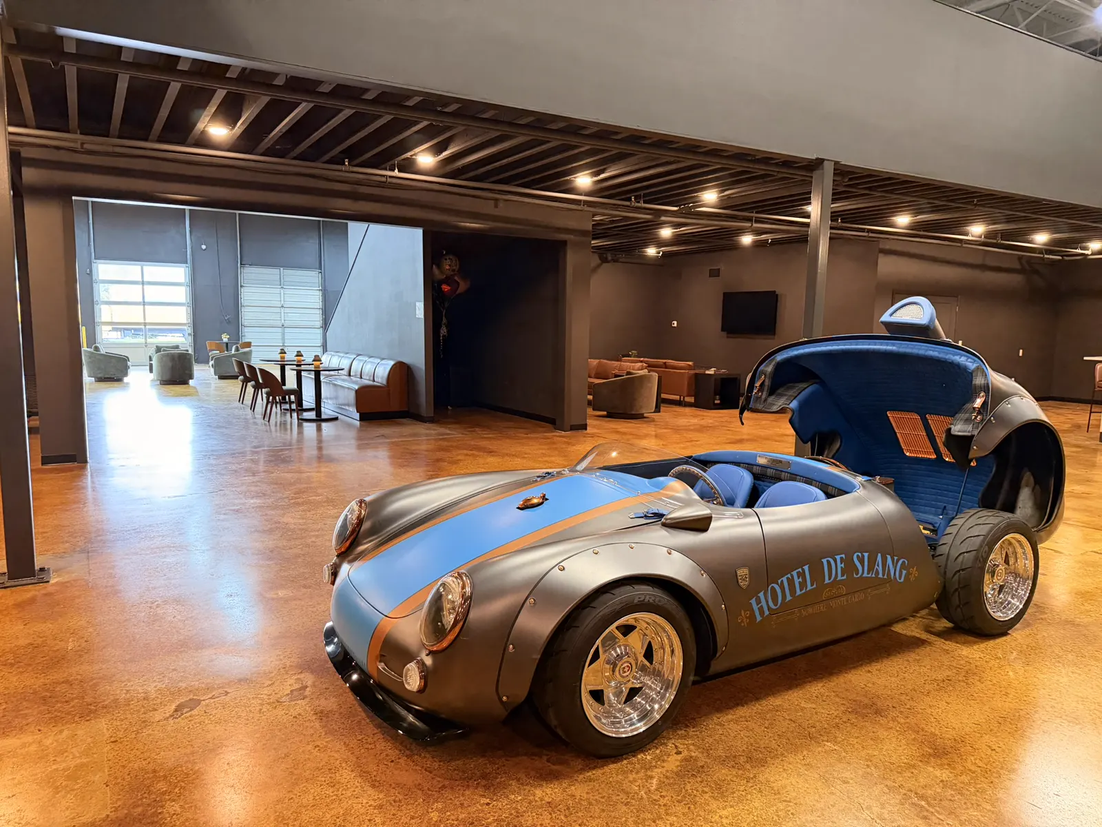 A blue and silver Porsche spyder on the Atlanta lounge floor, with the bar and seating behind