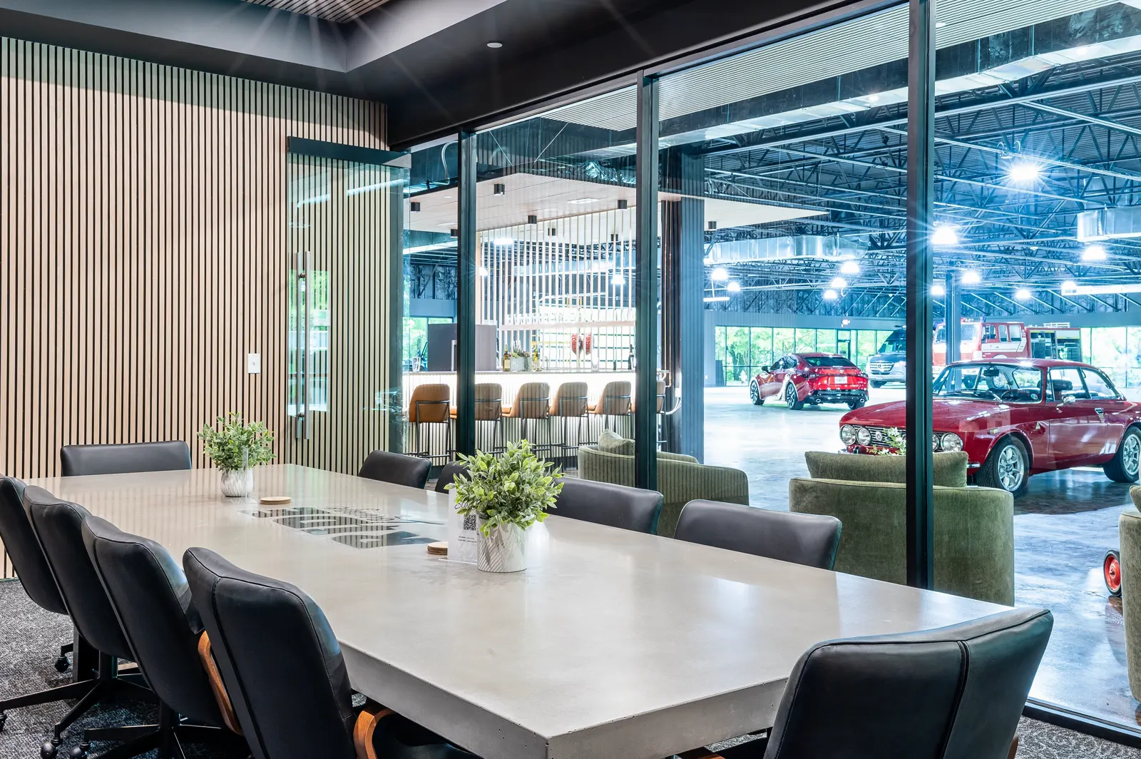 Long dining table beside the glass wall onto the cars